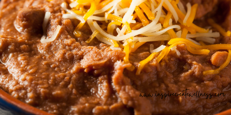 Refried pinto beans in a bowl w/ shredded cheese