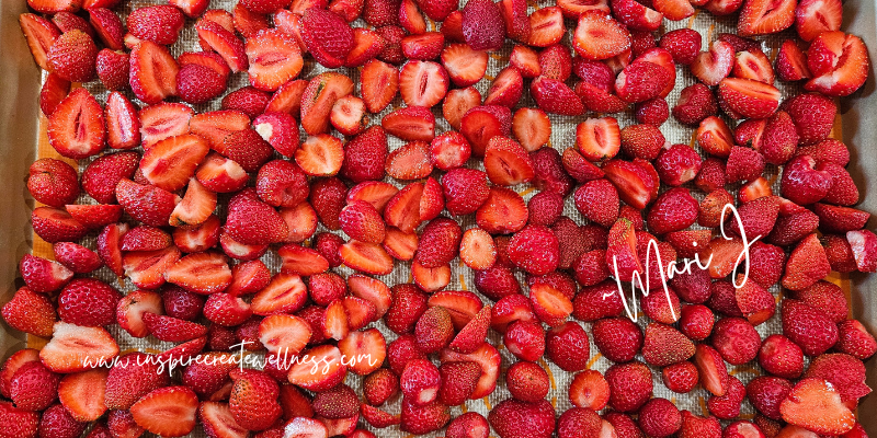 Clean fresh strawberries cut in half on cookie sheet