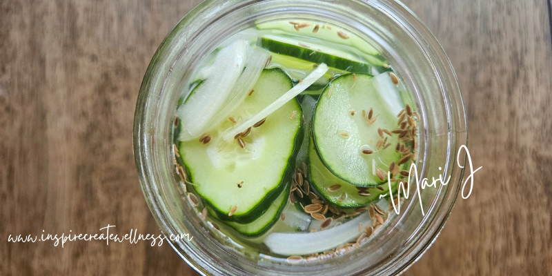 refrigerator pickle recipe - sliced cucumbers in a jar with dill seed, onion slices, and garlic