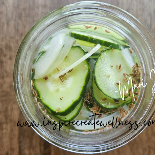 Sliced cucumbers, onions, spices, and vinegar in a quart size jar