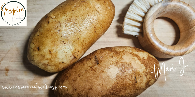 Freshly washed Organic Russet Potatoes on a cutting board with cleaning brush