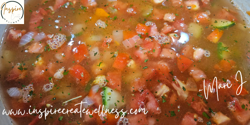 Freshly chopped tomatoes, carrots, celery, and onions simmering in vegetable broth for homemade soup