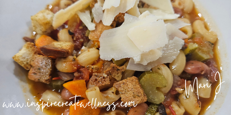 Hearty Homemade Minestrone Soup topped with shaved parmesan cheese in a white bowl