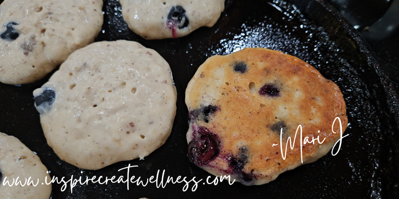 Blueberry Kefir Pancakes cooking on a iron skillet